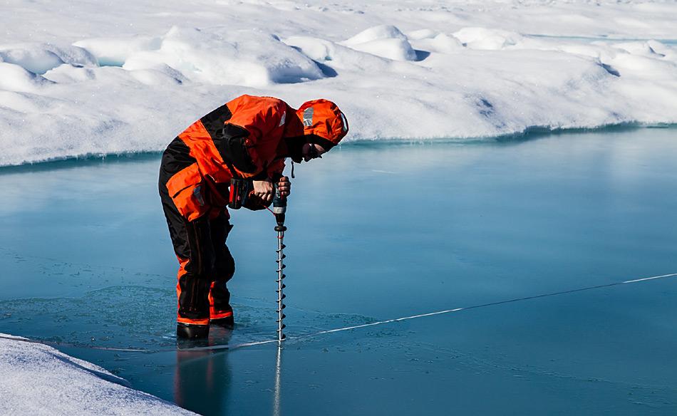 AWI-Meereisphysiker Marcel Nicolaus bohrt ein Loch in den Grund eines Schmelztümpels. Die Expedition IceArc hatte zum Ziel, die Biologie. Physik und Chemie des Meereises zu untersuchen und die Auswirkungen seines Rückganges auf das gesamte Ozeansystem bis in die Tiefsee zu erforschen. Foto: AWI, Martin Schiller
